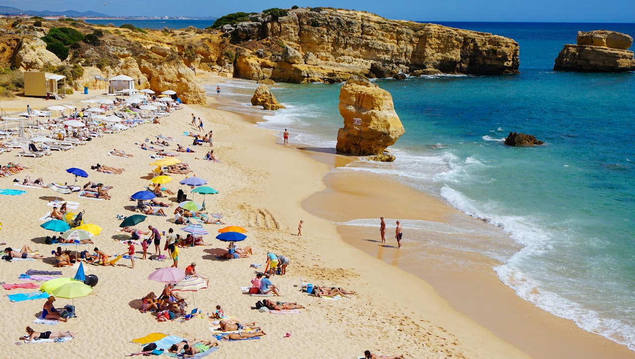 Busy beach with umbrellas beside rocky cliffs