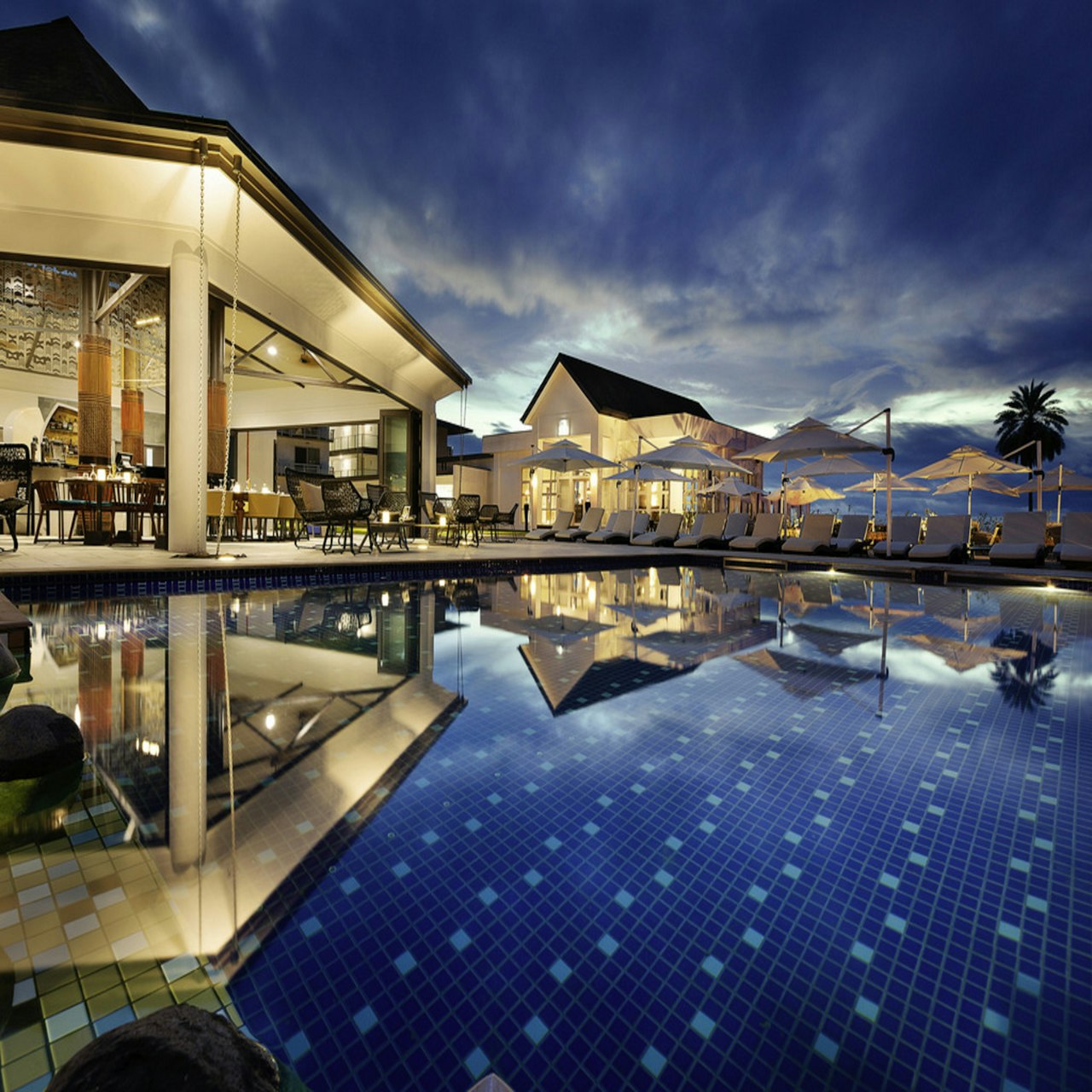 Resort pool reflecting the lit-up clubhouse at dusk